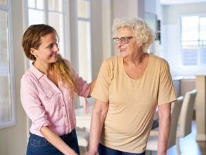 A cheerful care giver assists an elderly woman walk in her home. Senior Home Care in Enterprise, NV