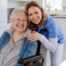 A caregiver enjoys her job as she smiles with a happy client representing the joy that can come from a home care career.