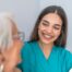 A caregiver smiles with an older client showing the results of successfully starting a new caregiving job.