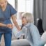 A caregiver demonstrates her caregiver skills by helping an older adult get up.