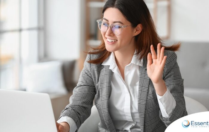 A well-dressed woman smiles and says hi on a videoconference, representing a candidate who is well-prepared for a caregiver interview.