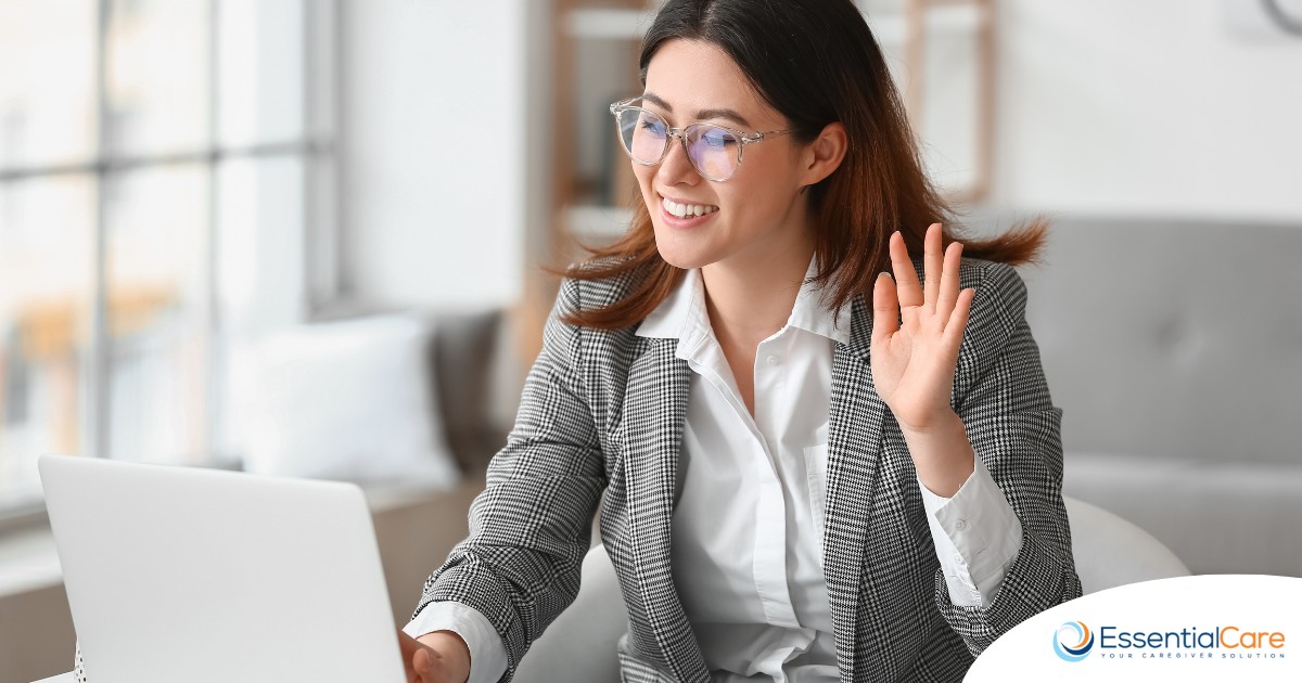 A well-dressed woman smiles and says hi on a videoconference, representing a candidate who is well-prepared for a caregiver interview.