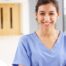 A woman in scrubs smiles, representing the good results that can come when caregivers branch out to become CNAs.