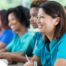 Several students in scrubs happily attend a class, representing caregiver training.