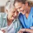 A woman in scrubs laughs with a senior woman, representing how caregiving can be a great career choice.