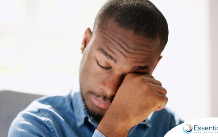 A man tiredly rubs his eyes, representing the exhaustion that can come with family caregiving.