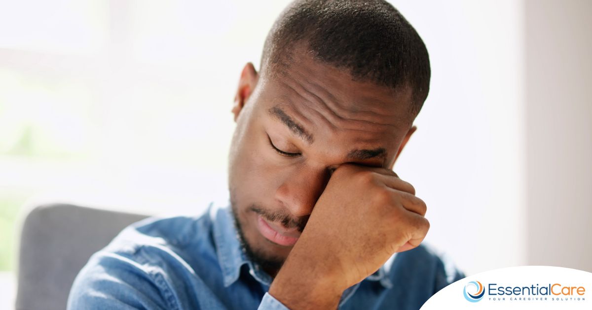 A man tiredly rubs his eyes, representing the exhaustion that can come with family caregiving.